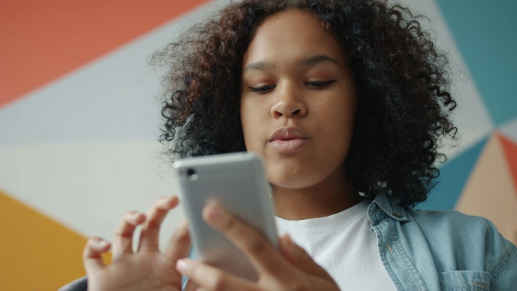 Young woman looking at her smartphone with colorful background; Gen Z credit scores