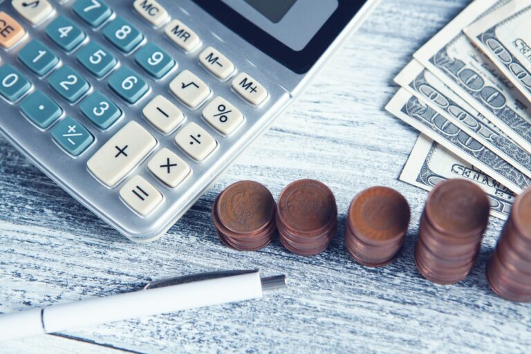 a calculator, pen, and money on a table; global payroll companies